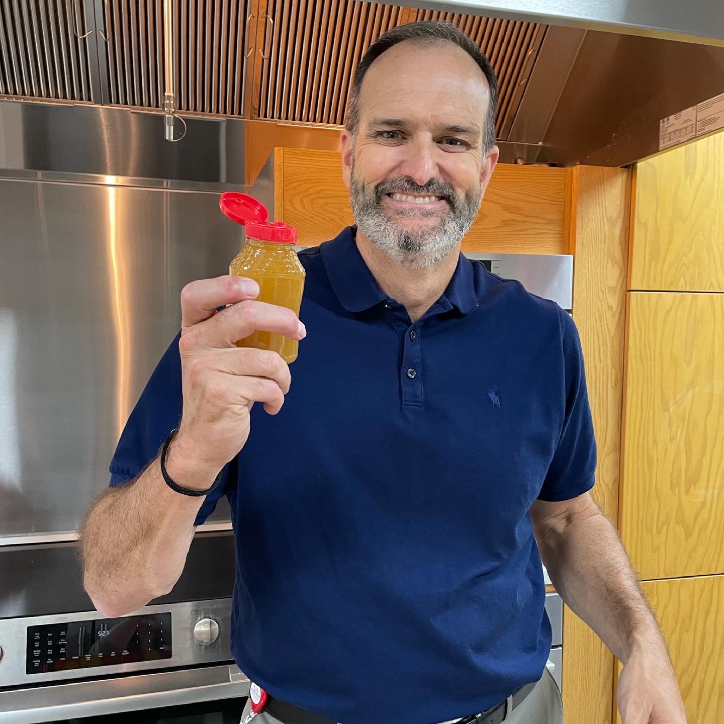 Dr. Bob Scott smiling and holding up a container of honey